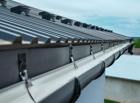 Close-up of a modern metal roof with newly installed seamless gutters secured along the fascia board – seamless gutter installation.