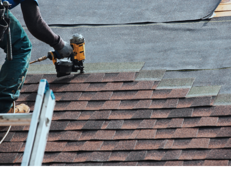Close-up of a roofing contractor using a nail gun during asphalt shingle roof installation on a residential home