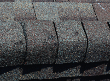 Close-up of asphalt shingles showing hail impact marks and cracks, highlighting the need for hail damage roof repair in Suwanee