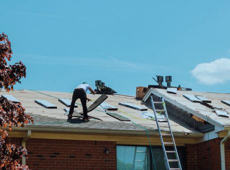 Emergency roofing contractor in Suwanee, GA, repairing storm-damaged shingles on a residential roof under sunny skies.