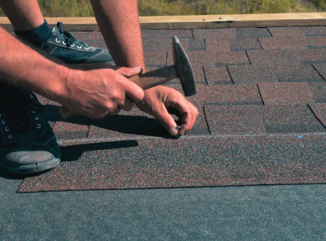 Roofer replacing a single asphalt shingle after hail damage, showing detailed hail damage roof repair and individual shingle replacement process